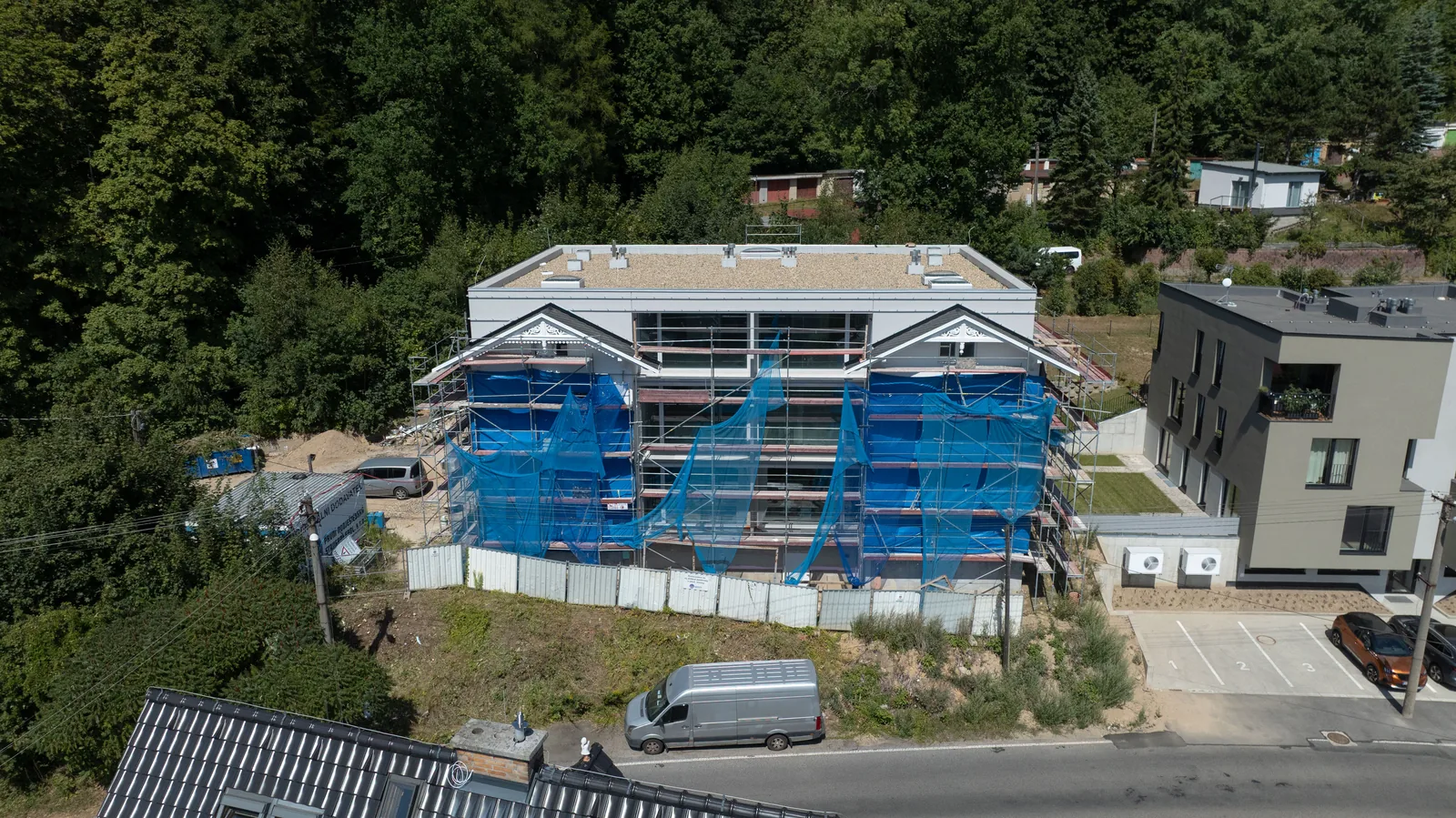 Švýcarská vila aus der Drohne, darüber der bewaldete Hang