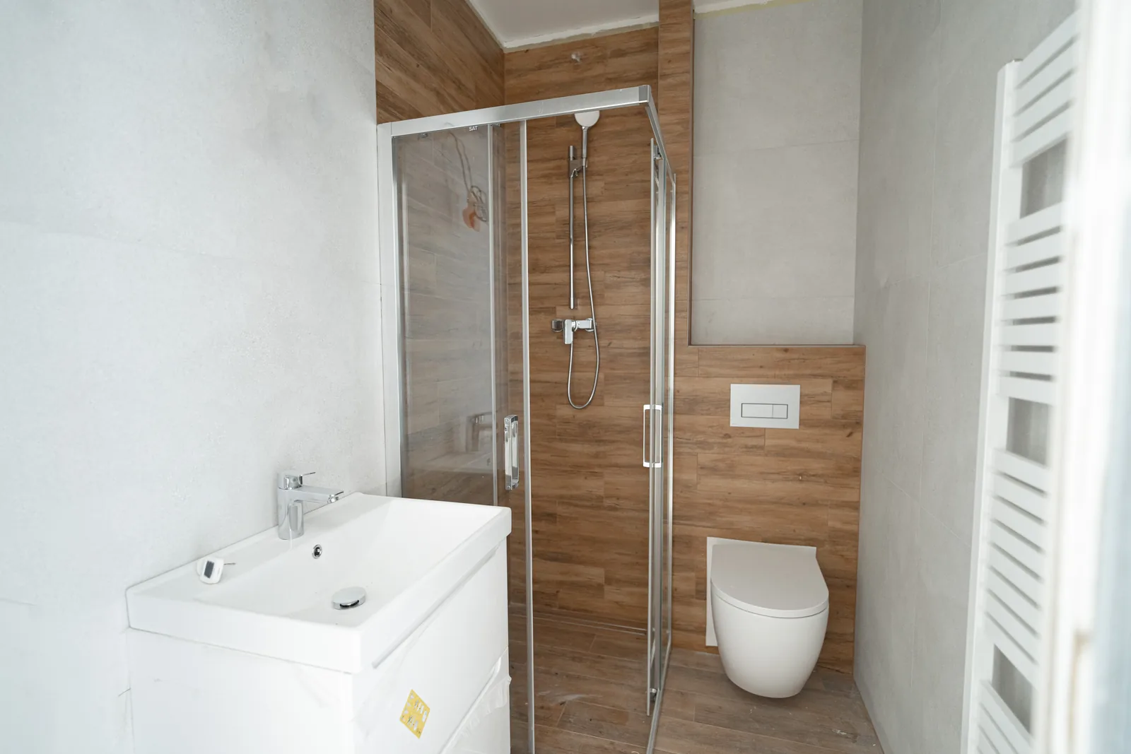 Fertiges Badezimmer eines 1+kk-Studios mit Dusche und Holztür